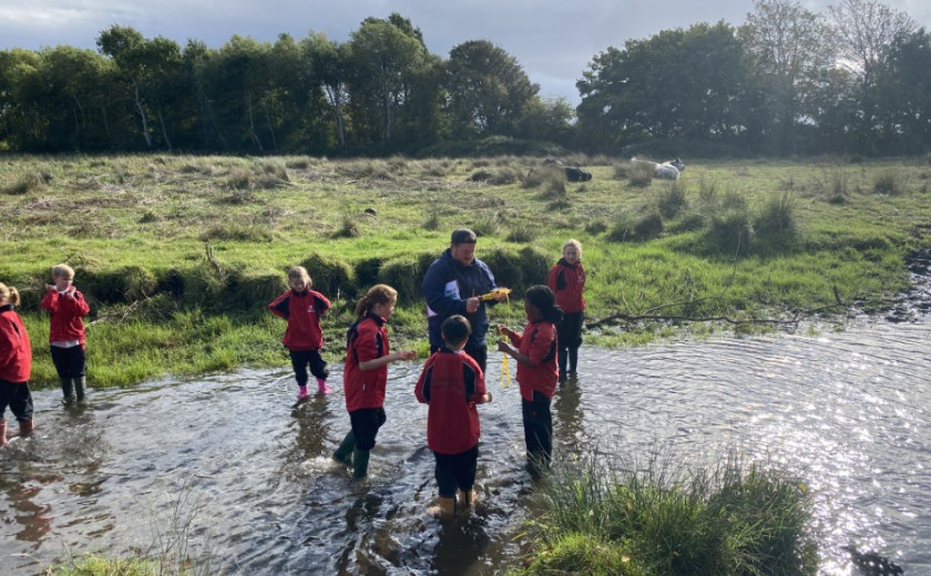 children measuring width and flow of a river
