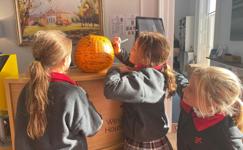 girls writing on a pumpkin
